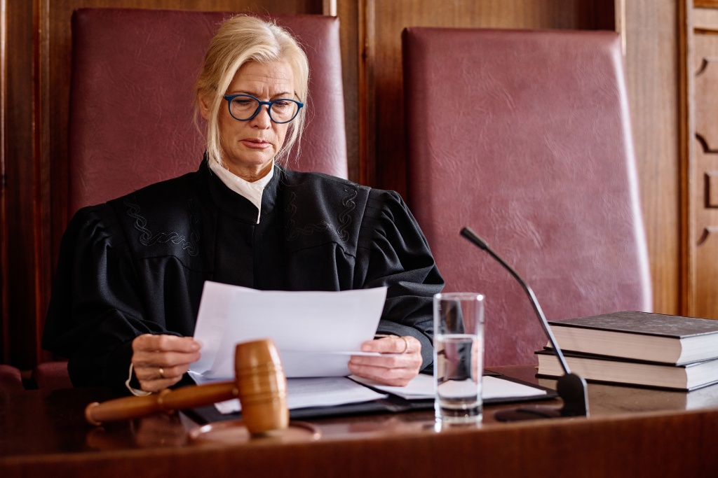 serious-blond-female-judge-black-mantle-looking-through-paper-document-before-trial-session.jpg судья